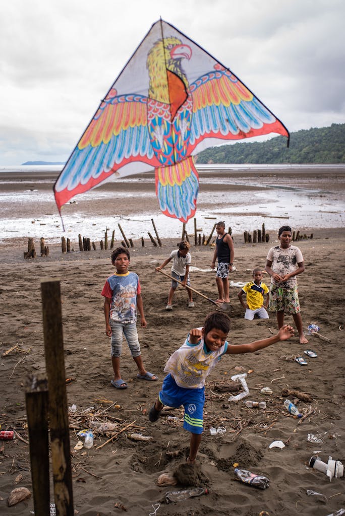 Group of children enjoying kite flying on a beach in Colombia, showcasing joy and teamwork.