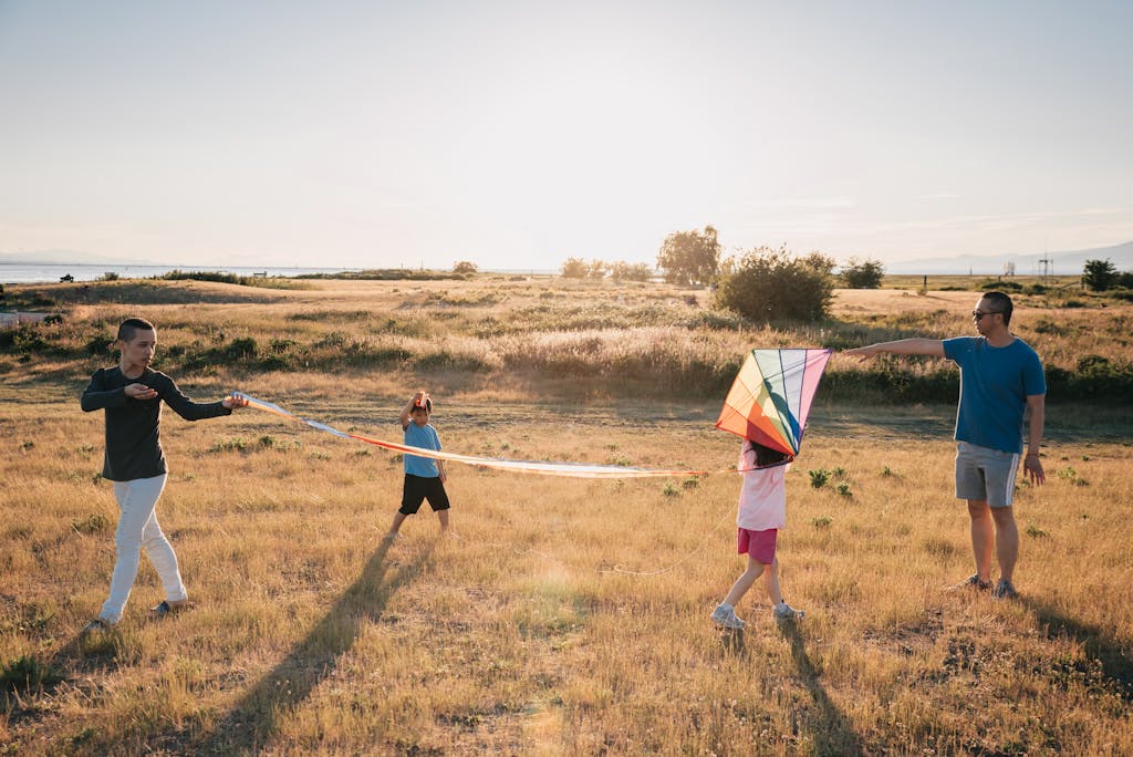 Happy family enjoying time flying a colorful kite in a sunny open field.
